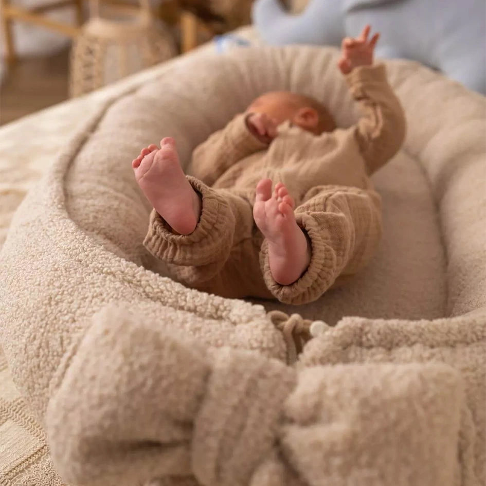 Baby Nestchen Lammfelloptik in Beige in Detailansicht und Babyfuß