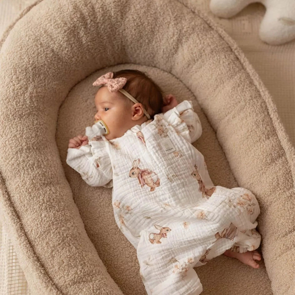 Baby Nestchen Lammfelloptik in Beige mit Baby auf Bett