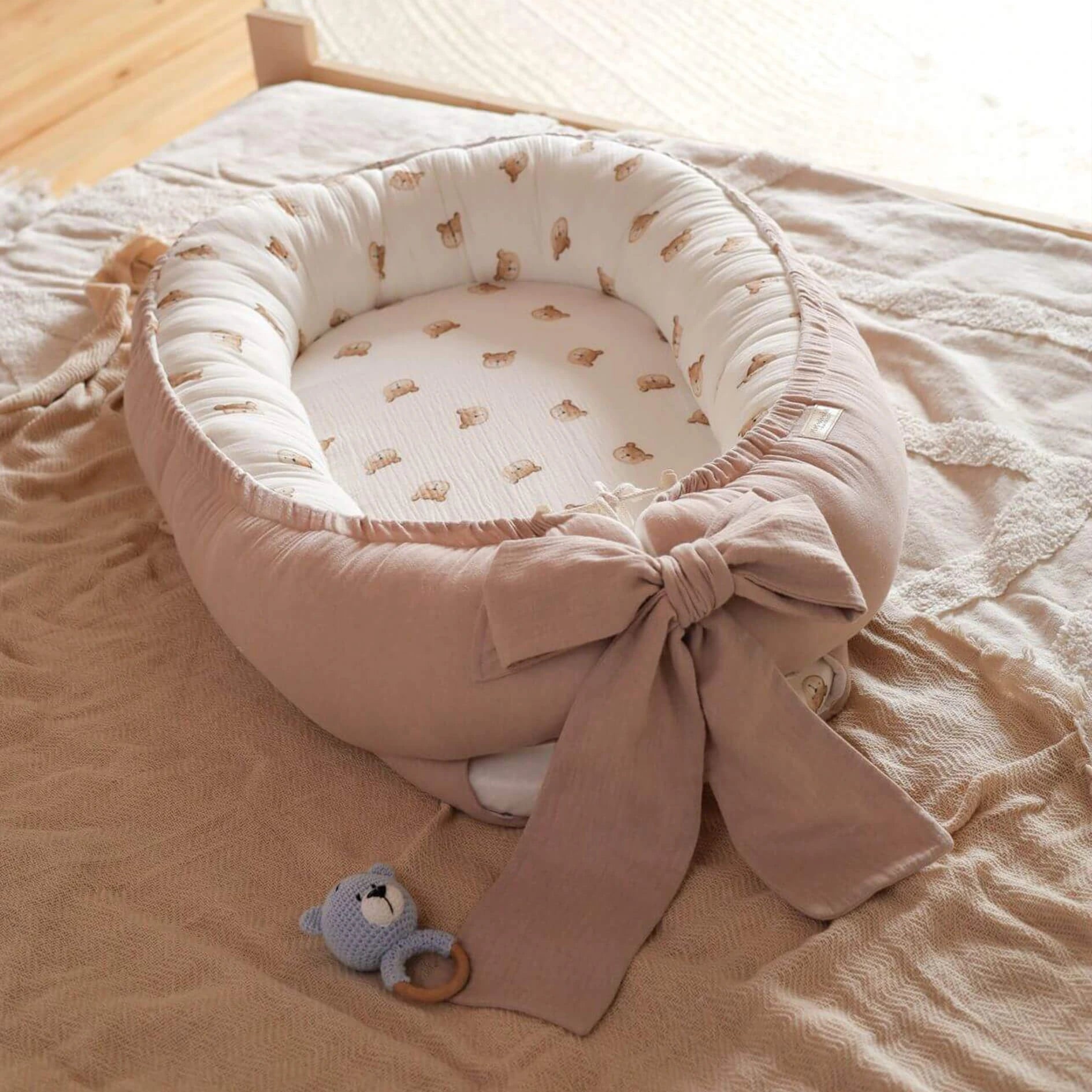 Baby Nestchen Rosa im Teddydesign in der Gesamtansicht auf Bett liegend