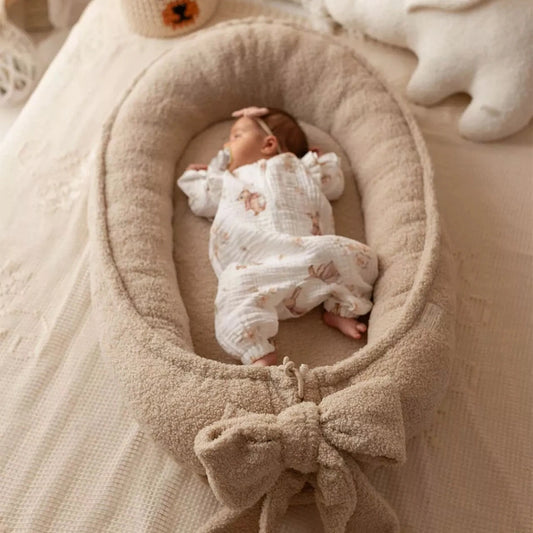 Baby Nestchen Lammfelloptik in Beige mit darin liegendem Baby